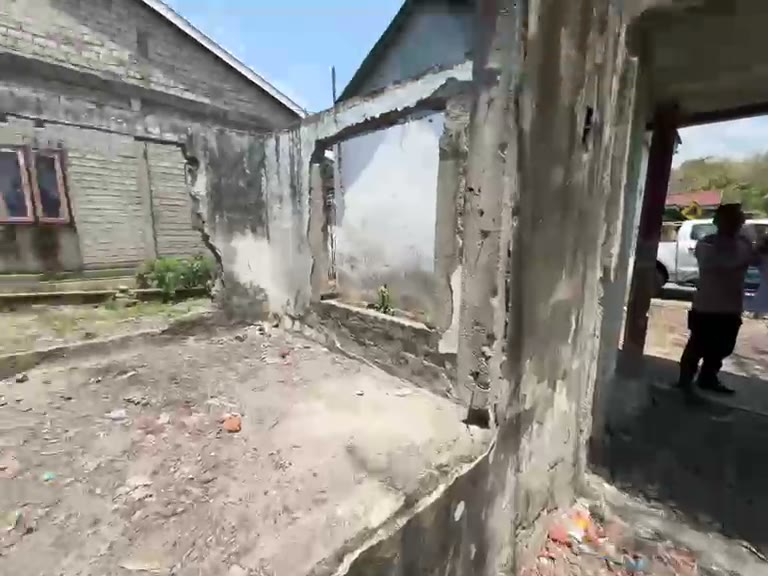 What remains of a house: bare walls around an empty, rubble-strewn floor.